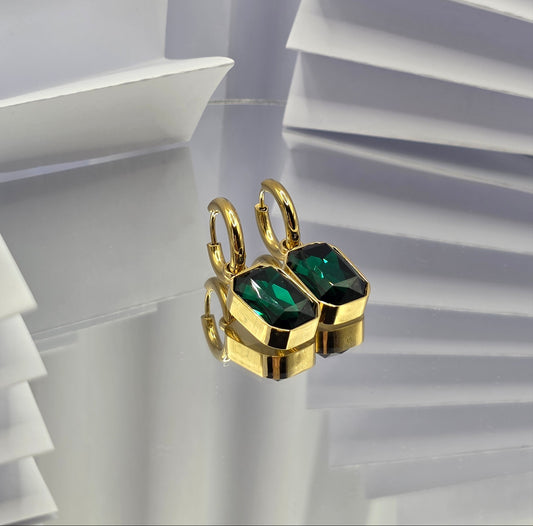 Gold ring with green gemstones on a white geometric background danavi aurum