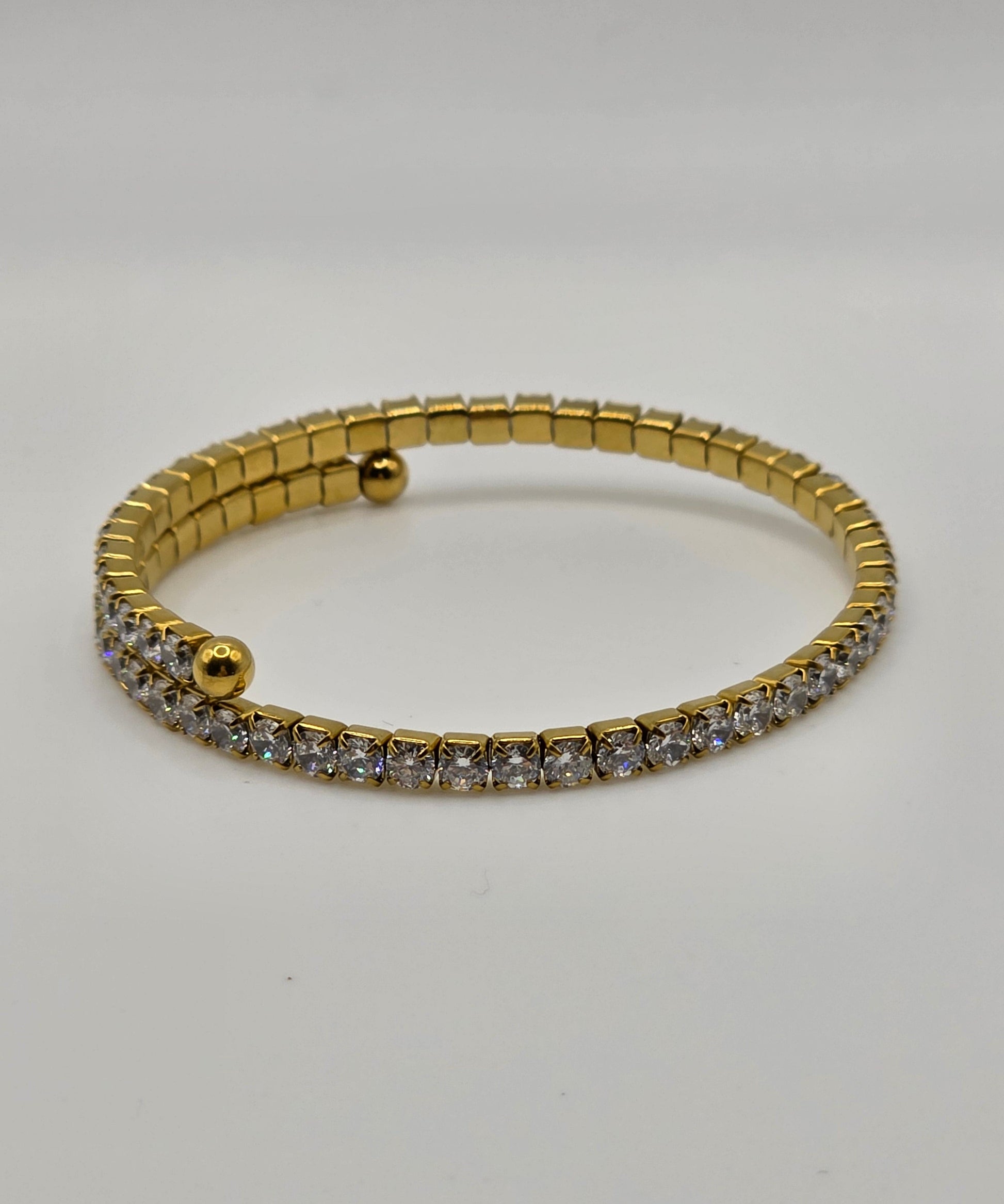 Gold bracelet with embedded stones on a light gray background danavi aurum