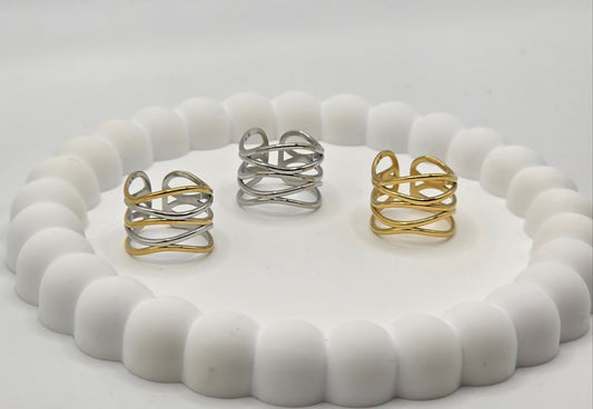 Set of gold and silver rings on a white textured stand against a light gray background