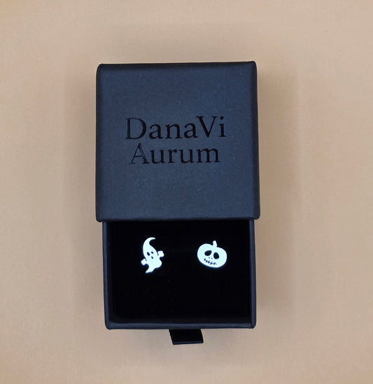 Black jewelry box with 'DanaVi Aurum' branding containing ghost-shaped earrings on a beige background.