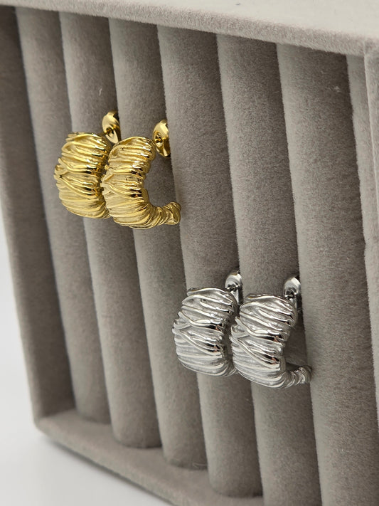Gold and silver hoop earrings on a gray jewelry display box danavi aurum