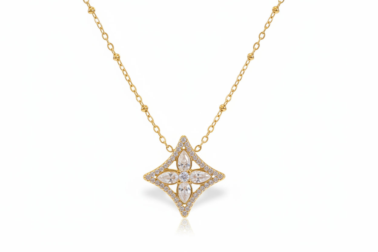 Gold necklace with a star-shaped pendant on a light background