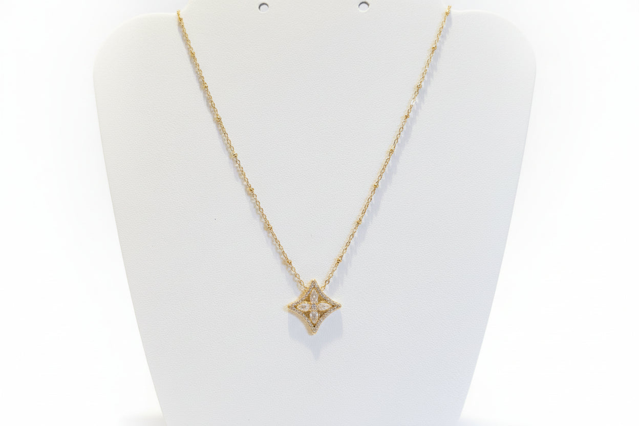Gold necklace with a star-shaped pendant on a white background